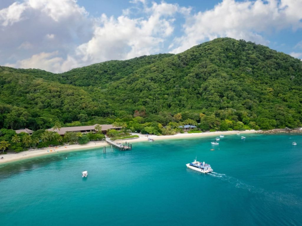 Fitzroy Island beach, jetty and boats beside rainforest-covered hills