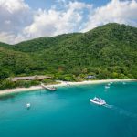 Fitzroy Island beach, jetty and boats beside rainforest-covered hills