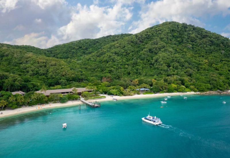 Fitzroy Island beach, jetty and boats beside rainforest-covered hills