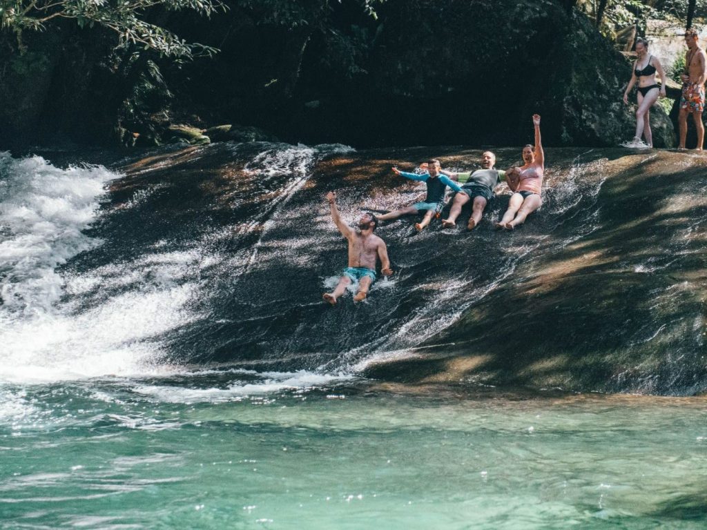 Visitors enjoying a waterfall swimming stop on a Cairns day tour
