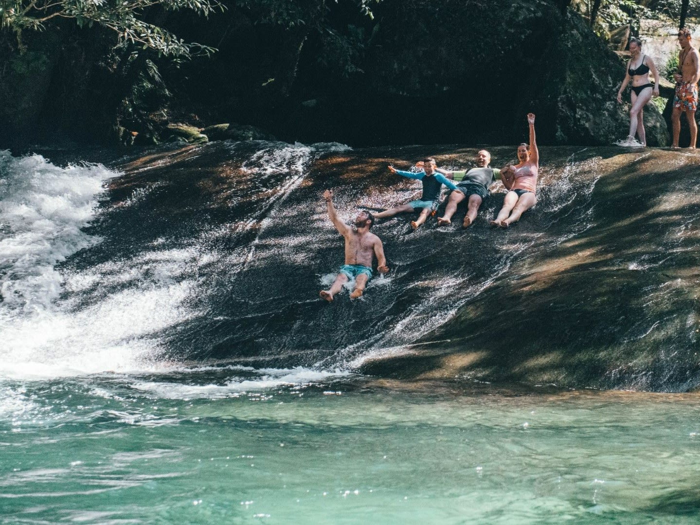Visitors enjoying a waterfall swimming stop on a Cairns day tour